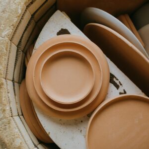 Warm-toned ceramic plates stacked inside a kiln, ready for firing.
